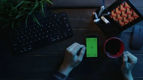 Overhead shot of man using his smartphone with green screen and drinking tea Stock Footage 81174149