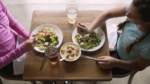 Overhead shot of mother and daughter having lunch at table in restaurant Stock Footage