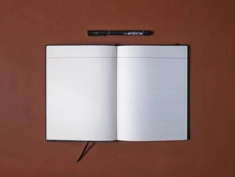 Overhead shot of an open notebook and a black pen Stock Photos