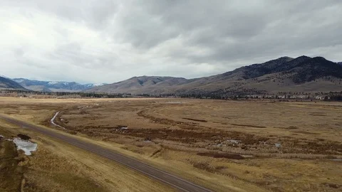 Overhead shot past empty highway toward rolling hills and snow capped mountai Stock Footage 125050667