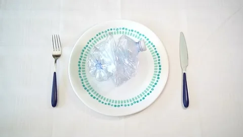 Overhead shot of a plate with a plastic bottle on it. Eating plastic Stock Footage 236840971