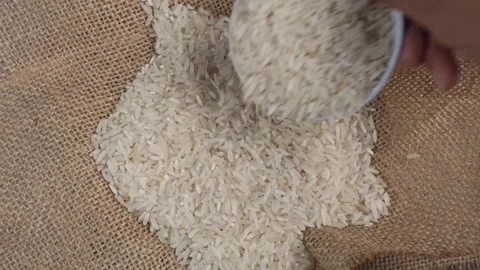 Overhead shot of pouring rice with mini bowl onto gunny sack Stock Footage 277782677