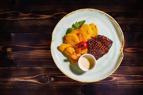 Overhead shot presenting a visually appealing steak with fried potatoes and s Foto stock