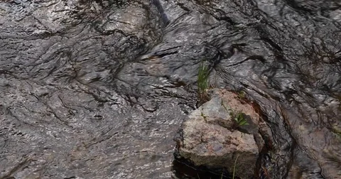 Overhead shot of river flowing around rock 4k 24fps Stock Footage 79326925