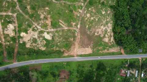 Overhead shot of a road cutting through a deforested area and lush vegetation Stock Footage 318300228