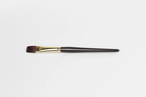An overhead shot of a small size flat brush with a white-colored surface in t Stock Photos