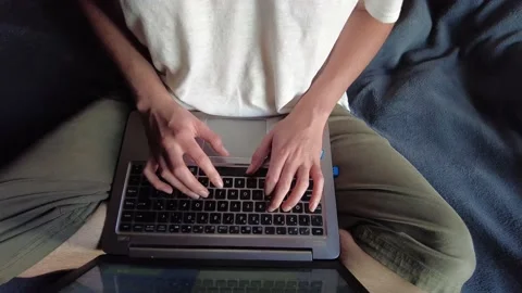 Overhead shot of a student or worker typing on a laptop sitting on a bed Stock Footage 147360800