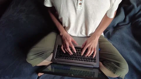 Overhead shot of a student or worker typing on a laptop sitting on a bed Stock Footage 147360978