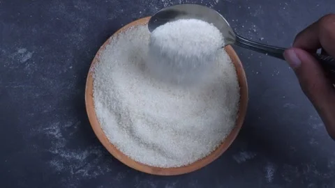 Overhead shot view of hand stirring sugar grain in wooden bowl with spoon 库存影片 281064162