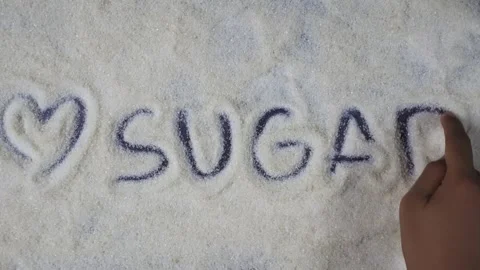 Overhead shot view of hand writing sugar word with love symbol on sugar grain 库存影片 280747385