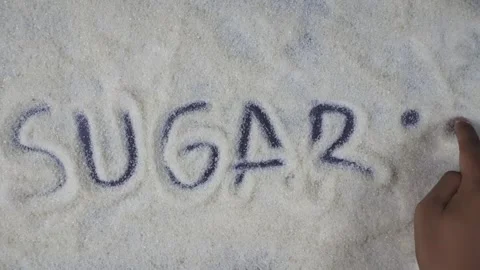 Overhead shot view of hand writing sugar word with smile emoticon on sugar 库存影片 281060595