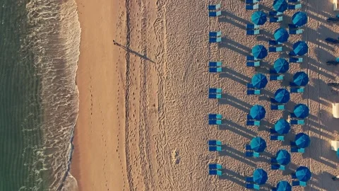 Overhead shot of waves breaking on beautiful tropical beach chairs and umbrellas Stockbeeldmateriaal 280507515