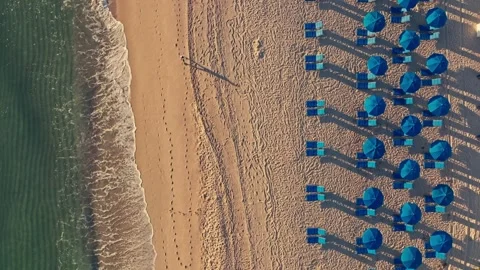 Overhead shot of waves breaking on beautiful tropical beach chairs and umbrellas Stock Footage 280507516