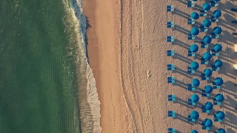 Overhead shot of waves breaking on beautiful tropical beach chairs and umbrellas Stockbeeldmateriaal 280507534