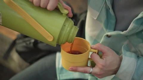 Overhead shot of white backpacker pouring coffee into yellow cup on bench during Stock Footage 331201913