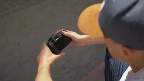 Overhead Shot of White Man with Hat Holding Small Black Mirrorless Camera Stock Footage 90309844