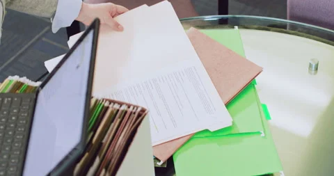 Overhead shot of a woman sorting though files and logging them onto a tablet Stock Footage 138665014