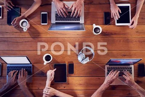 Overhead shot of young adults using technology at a table Stock Photos