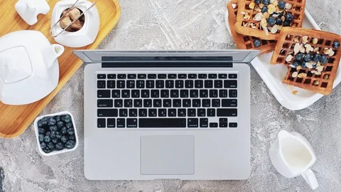 Overhead shot of young female using laptop and having a waffle snack Stock Footage 92893698