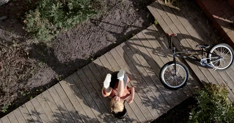 OVERHEAD slow motion shot of a kid falling from a bicycle while doing trick 스톡 동영상 251629344