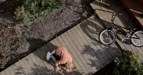 OVERHEAD slow motion shot of a kid falling from a bicycle while doing trick 스톡 동영상 251629363
