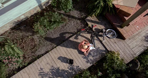 OVERHEAD slow motion shot of a kid falling from a bicycle while doing trick 스톡 동영상 251647199