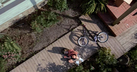OVERHEAD slow motion shot of a kid falling from a bicycle while doing trick 스톡 동영상 251647210