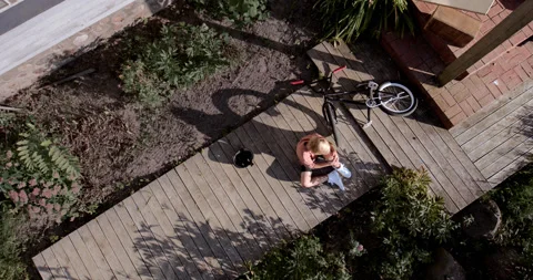 OVERHEAD slow motion shot of a kid falling from a bicycle while doing trick 스톡 동영상 251647237