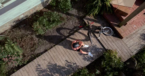 OVERHEAD slow motion shot of a kid falling from a bicycle while doing trick 스톡 동영상 251647249