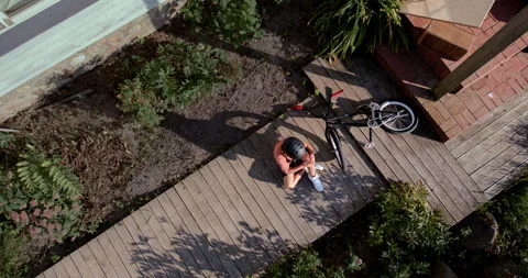 OVERHEAD slow motion shot of a kid falling from a bicycle while doing trick 스톡 동영상 251796597