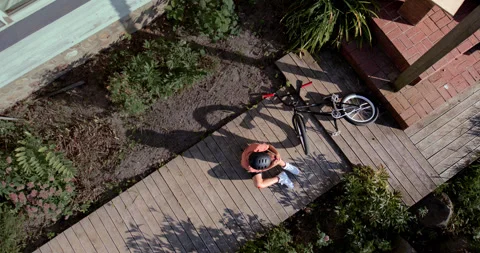 OVERHEAD slow motion shot of a kid falling from a bicycle while doing trick 스톡 동영상 251944629