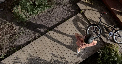 OVERHEAD slow motion shot of a kid picking his bicycle after falling Stock Footage 252565089