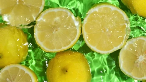 Overhead slow motion shot of lemon halves splashing in clear liquid background Stock Footage 345226882