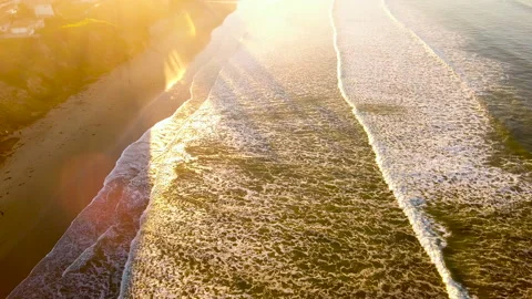 Overhead of surf and beach tilts up to sunrise. 4k Aerial Stock Footage 145524036