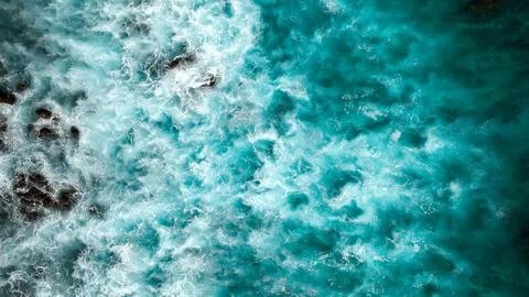Overhead top down drone view of waves crashing on the shore with foam blue water Stock Photos