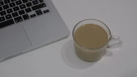 Overhead top view of a clear glass mug of coffee next to a laptop keyboard on a Stock Footage 346505874