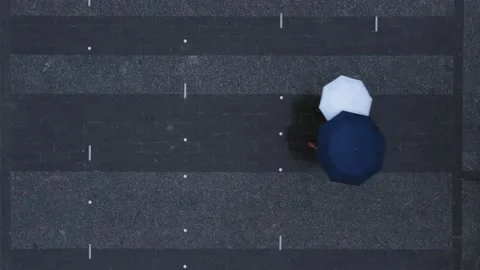 Overhead top view couple passing by walking with umbrella by town square Stock Footage 150043345