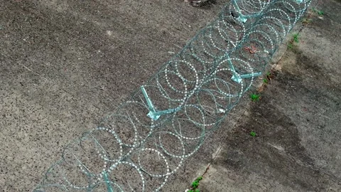 Overhead Track Along Parallel Razor Wire Rows on Concrete Stock-Footage 344120050