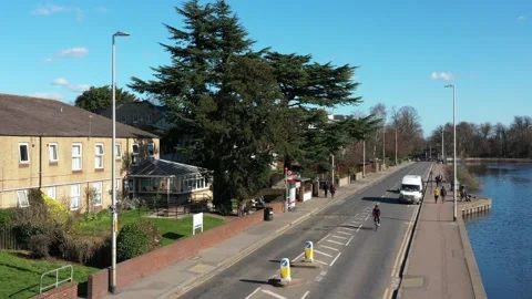 OVERHEAD TRACKING OF A CYCLIST RIDING ALONSIDE A POND, ENGLAND. AERIAL Stock-Footage 150166133