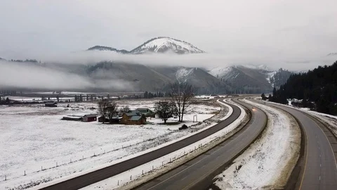 Overhead tracking shot of a snow covered ranch with mountain range and cars p Stock Footage 124616354