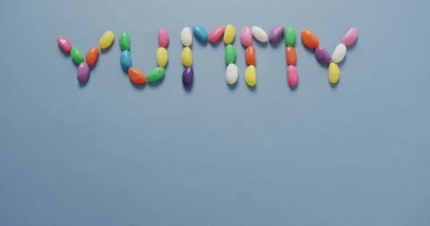 Overhead video shows text from multi-colored sweets on blue, space for copy Stock Footage 338433768