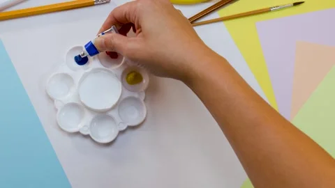Overhead View of Artist Squeezing Blue Acrylic Paint onto White Palette Stock Footage 327176634