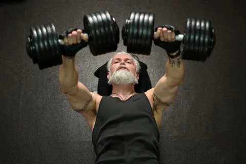 An overhead view of an athletic gray-haired man with a beard and tattoos, tra Stock Photos