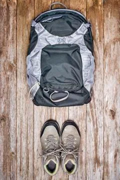 Overhead view of a backpack and hiking boots on a wood surface Stock Photos