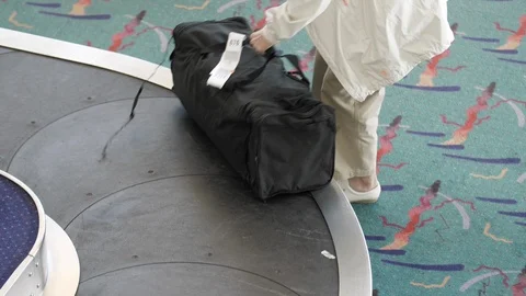 Overhead View of Baggage Carousel with Elderly Woman Traveler Retrieving Luggage Stock Footage 124767079