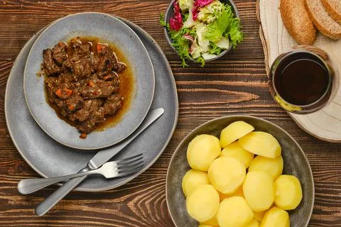 Overhead view of beef or deer ragout with potato, salad and wine Stock Photos