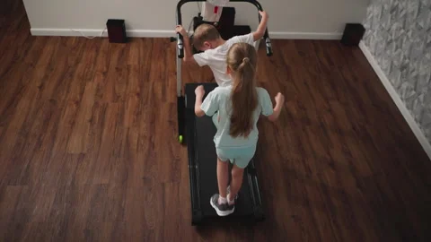 Overhead View of Boy Looking Back While Girl Behind Avoids Falling on Treadmill Vídeos de archivo 310207331