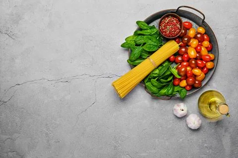 Overhead view of a bunch of raw spaghetti with spinach, tomato, garlic and ol Foto stock