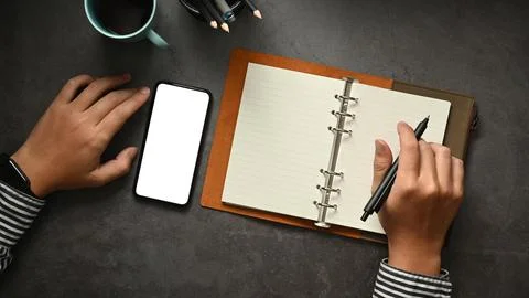 Overhead view of businessman using mobile phone and making notes on notepad Stock Photos