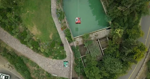 OVERHEAD VIEW OF CABLE CAR AERIAL TRAMWAY PASSES TROUGH A POOL, TREES, ROADS 4K Stock Footage 102557673